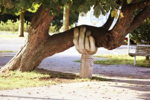 Wooden hand holding up a tree.